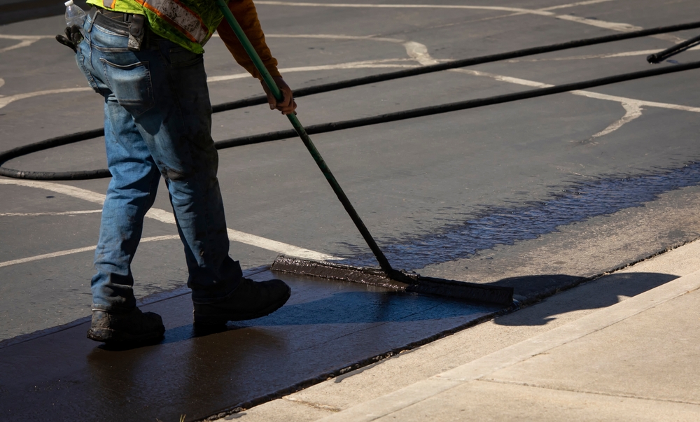 Worker,using,a,sealcoating,brush,during,asphalt,resurfacing,project